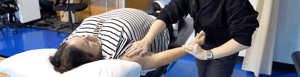 Physical therapy patient lays on her back on a treatment table to do rehabilitation after surgery.