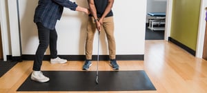 Physical therapist evaluating golfer's swing mechanics and posture at EW Motion Therapy clinic in Birmingham, Alabama.
