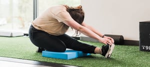 Gymnast performing flexibility training and stretching exercises on balance pad at EW Motion Therapy clinic.