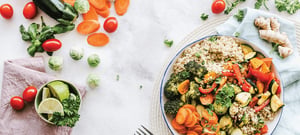 Healthy anti-inflammatory meal bowl with quinoa and roasted vegetables alongside fresh produce for nutrition counseling and injury recovery support at a physical therapy clinic.