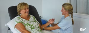 Woman receiving physical therapy for elbow pain, performing a guided exercise with a physical therapist to improve strength and mobility.