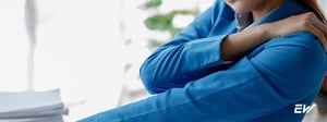 Woman experiencing shoulder, spine, and nerve pain, holding her shoulder due to radiating nerve symptoms commonly treated with physical therapy.