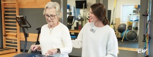 Physical therapist assisting an older adult with ALS during neurologic physical therapy to improve mobility and safety.