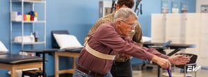 Physical therapist assisting an older adult with balance disorder treatment during supervised physical therapy.