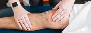 Therapist performing manual therapy on a person’s lower leg to manage chronic pain.