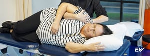 Person receiving physical therapy treatment for frozen shoulder while lying on a treatment table.
