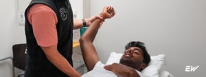Person receiving physical therapy treatment for golfer’s elbow while lying on a treatment table.