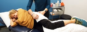 Physical therapist performing a side-lying hip assessment to evaluate a suspected hip labral tear.