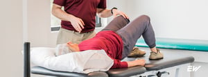 Older adult performing a guided rehabilitation exercise for joint degeneration with the help of a physical therapist.