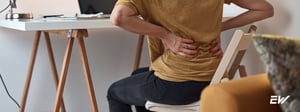 Person holding lower back due to SI joint pain, a condition treated with physical therapy.