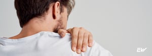 Man holding shoulder due to shoulder impingement pain, a condition treated with physical therapy.