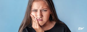 Woman experiencing jaw pain from TMJ disorder, a condition treated with physical therapy and TMJ rehabilitation.