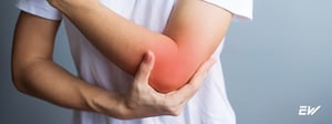 Person holding elbow due to tennis elbow pain, a condition treated with physical therapy.