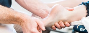Physical therapist performing hands-on assessment and treatment for an ankle sprain during physical therapy.