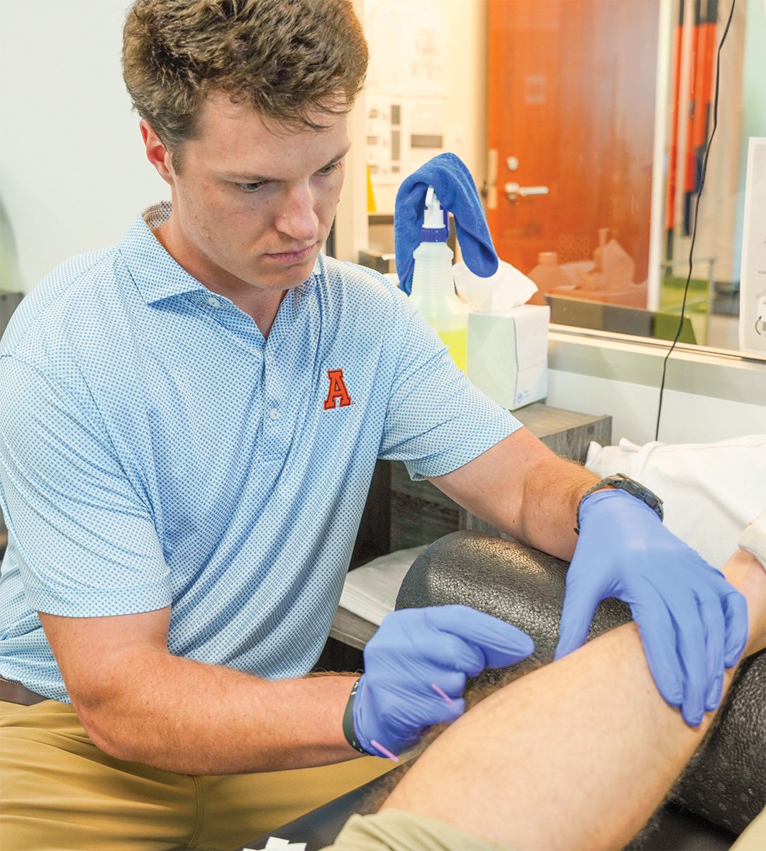 Licensed physical therapist performing dry needling treatment on a patient's knee to relieve muscle pain and trigger points at a physical therapy clinic.