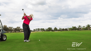 An elderly man prepares to swing at a golf ball.