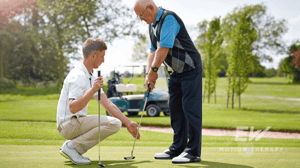 An older golfer gets club assistance from a younger pro.