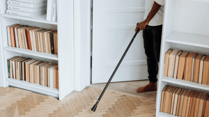 A man walks into a room with his cane.