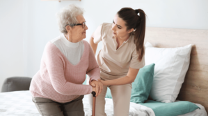 A home care nurse helps an elderly lady stand up.