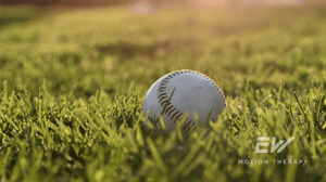 A baseball sits in the grass.