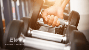 A hand picks up a dumbbell from a weight rack.