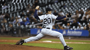 A baseball pitcher winds up to throw.