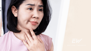 A woman with Bells palsy looks in the mirror as her face droops.