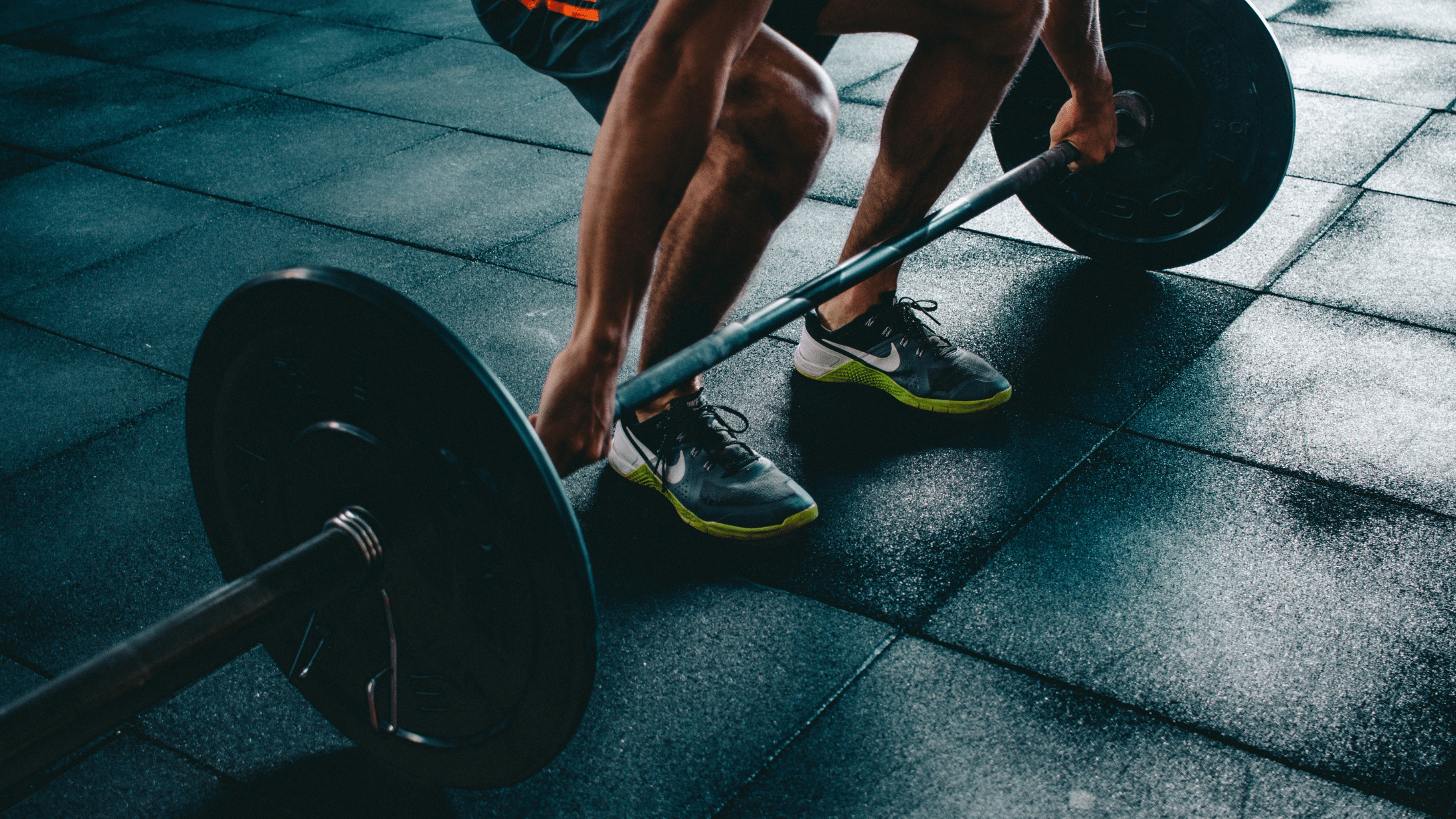A person about to lift a barbell off the ground.
