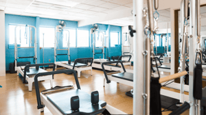 Pilates studio with reformers in a room with mirrors.