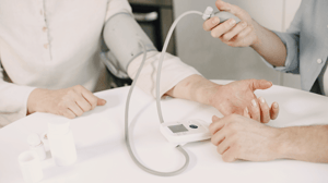 Two people operate a blood pressure cuff.