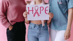 Three women stand holding a pink 