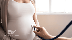 A doctor holds a stethoscope up to a pregnant woman's stomach.