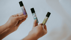 Hands holding multiple roll-on oils.