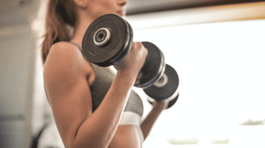 From the side, a woman lifts weights.