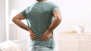 A man grips his lower back in pain.