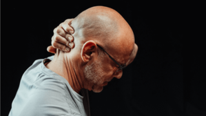 A man grips the back of his neck.