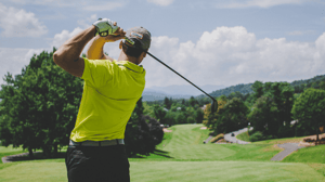 A man swings a golf club. 