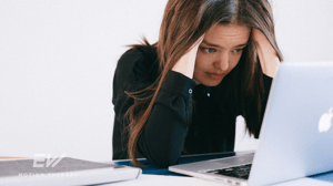 A woman sits stressed in front of her computer.