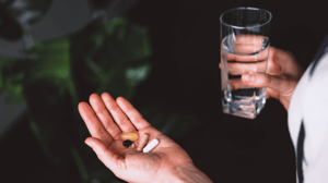 A person holds a glass of water to take supplements.