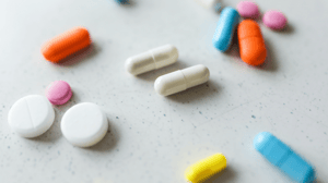 Different colored pills spread on a white surface.