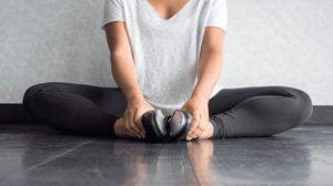 A dancer in tap shoes sits in a butterfly stretch on the floor.