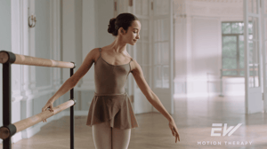 A dancer stands at a barre.