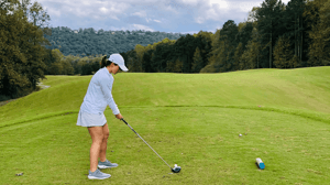 A girl about to swing a golf club on a golf course.