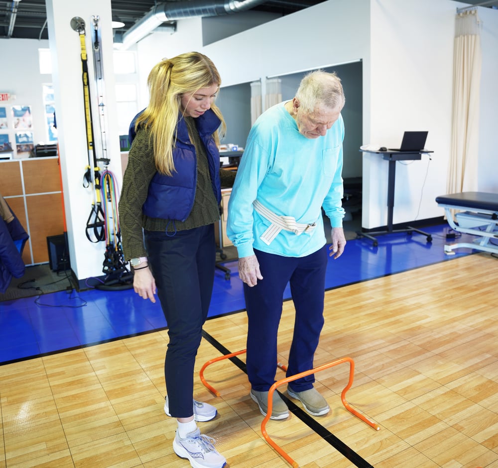 Physical therapist guides patient through specialized exercise for neurological condition. Physical therapist guides patient through specialized exercise for neurological condition.