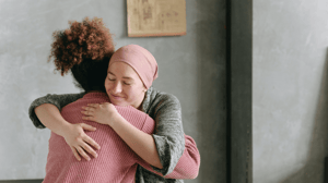 Two women hug, one in a headscarf.