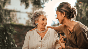 An old woman and a younger woman sit talking outside.