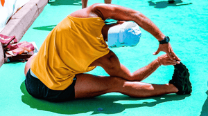 A man sits and stretches his left side.