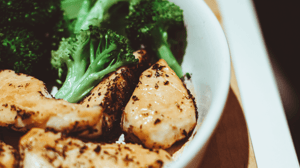 A bowl with grilled chicken and broccoli. 