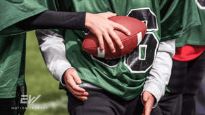 Close-up image of young football players holding a ball.