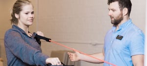 Personal trainer guiding woman through resistance band exercise at EW Motion Therapy clinic in Birmingham, Alabama. 